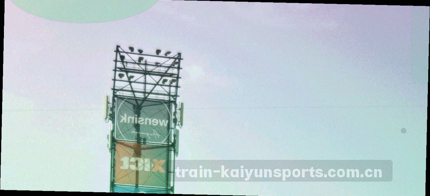 赛前球场看台空镜，灯光尚未全亮，冷调硬光下的座椅与跑道
